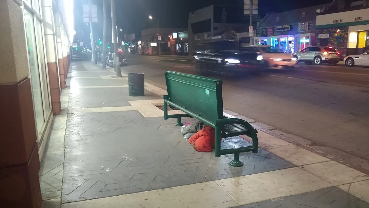Homeless camping under a street bench